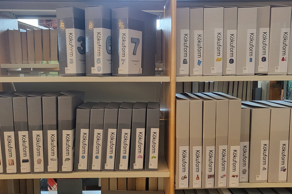 Mynd af pappahólfum í hillu sem innihalda kökuform