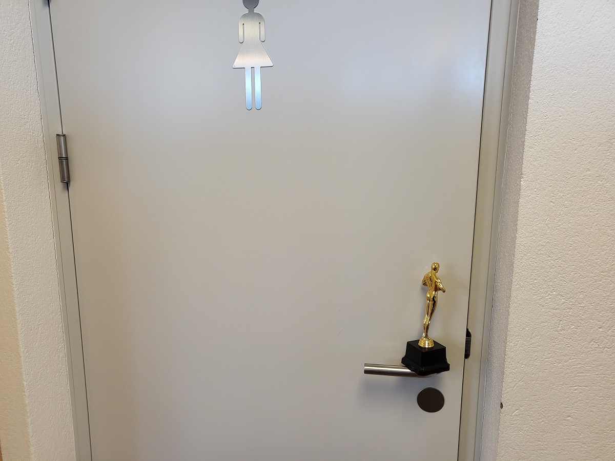 Mynd af Óskarsstyttu fyrir framan klósetthurð