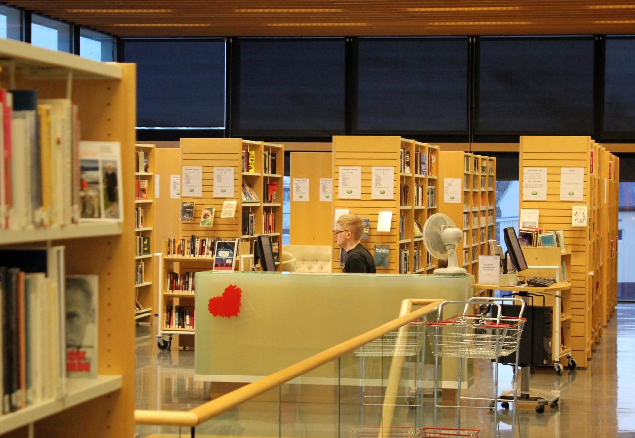 Shelves all around with books and a desk with an employee behind it