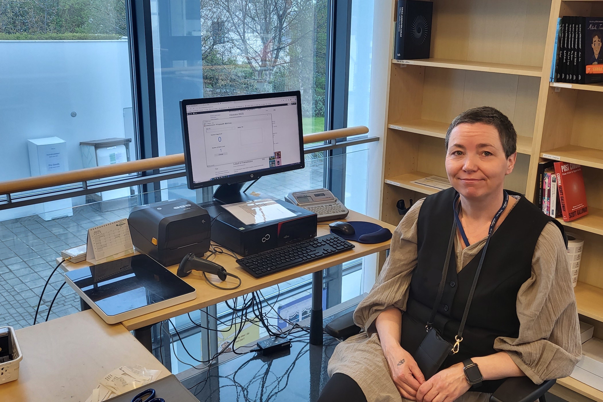 Mynd af konu sitjandi við tölvu og borð