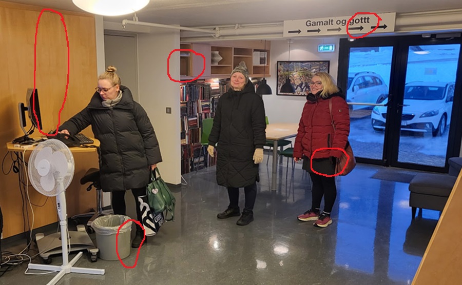 Women coming to work in the library, computer on a stand and books in shelves in the backgroun