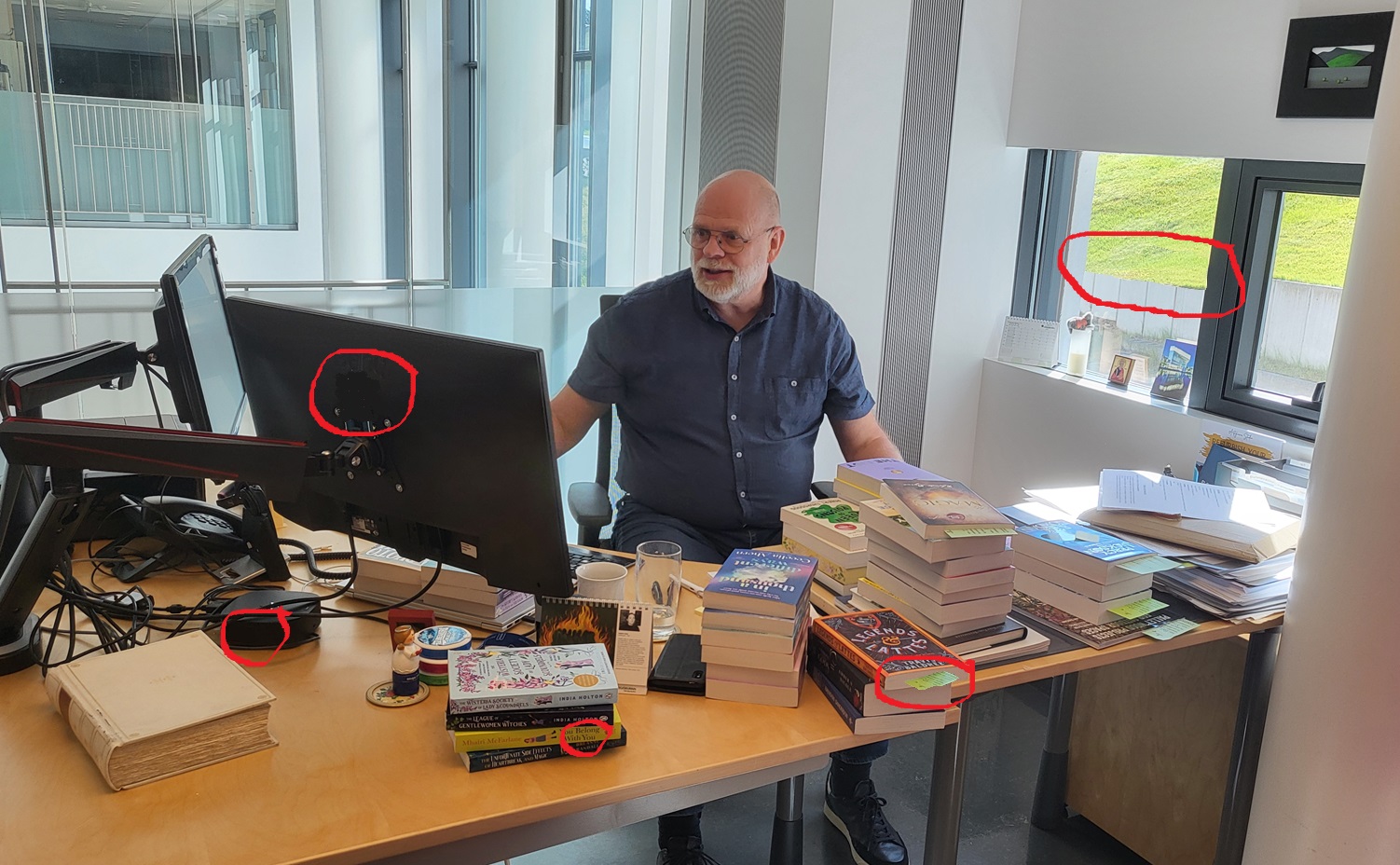 Man behind a desk with computer and lot of books on the table