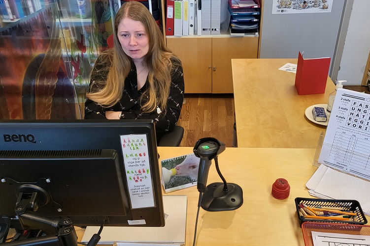 Mynd af konu sitjandi og vinnandi við tölvu og starir á skjáinn